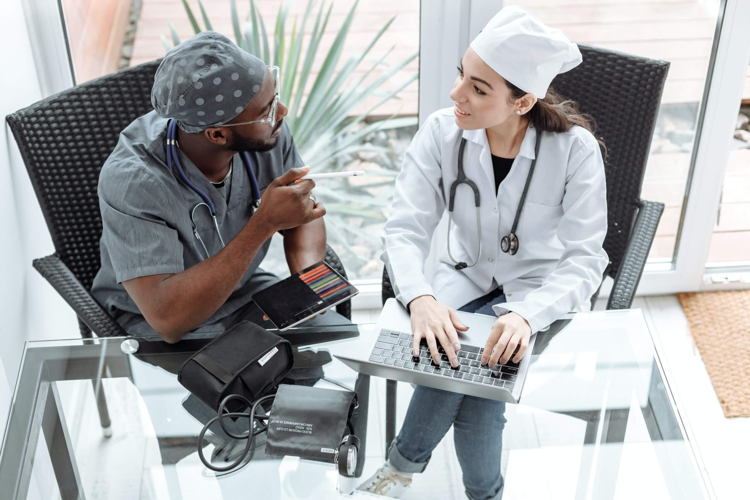 Due medici seduti su sedie di fronte a una scrivania, impegnati in una conversazione medica.