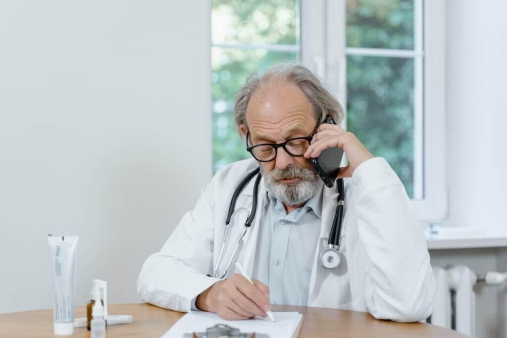 Medico anziano che fornisce assistenza dedicata e comunicazione professionale durante una telefonata.